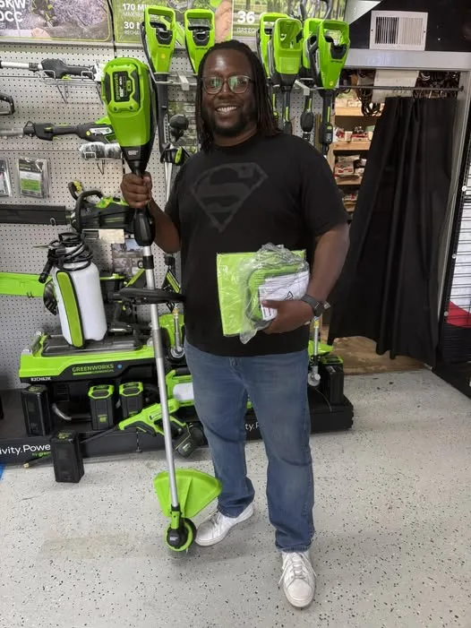 Customer holding a Greenworks string trimmer and accessories inside the shop