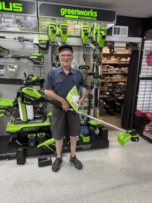 Customer standing with a Greenworks commercial trimmer inside the shop